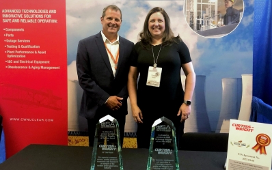 Curtiss-Wright's Joe Cinelli and Theresa Sutter stand behind a table with two award trophies